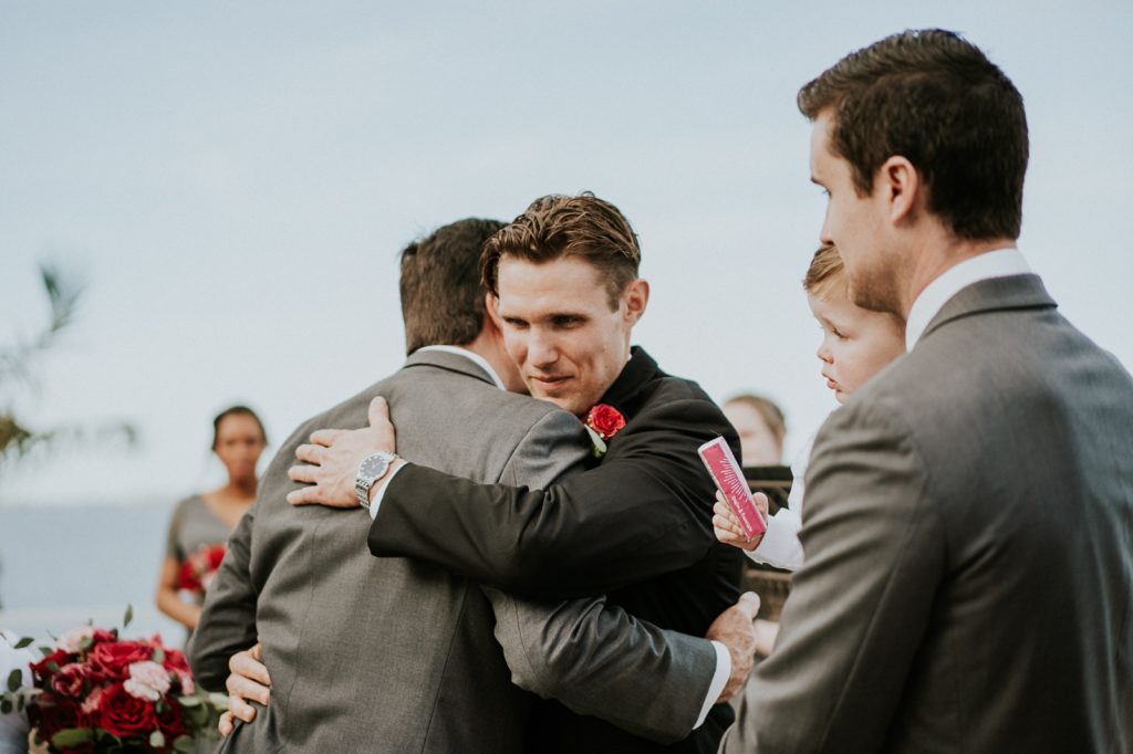 Groom hugging father of the bride in wedding ceremony