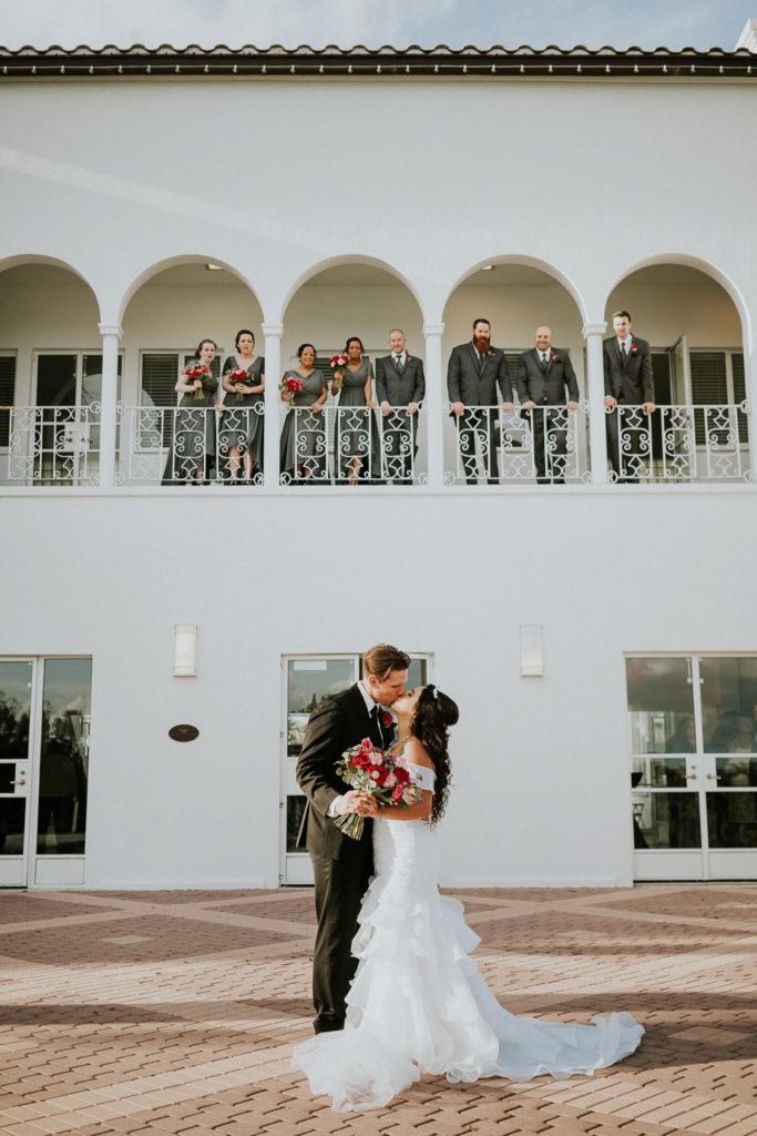 Tuckahoe Mansion wedding couple kiss below bridal party on balcony Jensen Beach FL photography