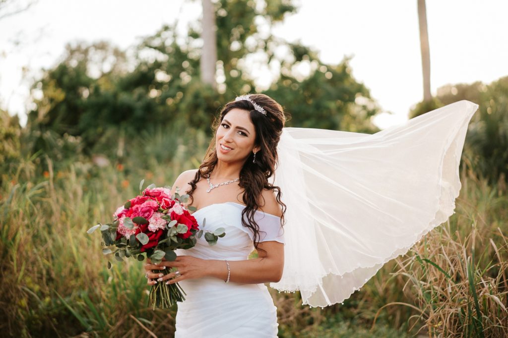 Bride holding pink rose bouquet wears veil blowing in the wind South FL wedding photography