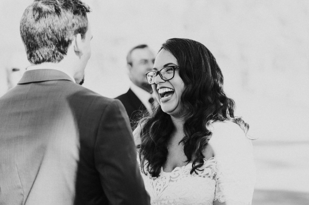 Black and white photo of bride laughing during ceremony vows