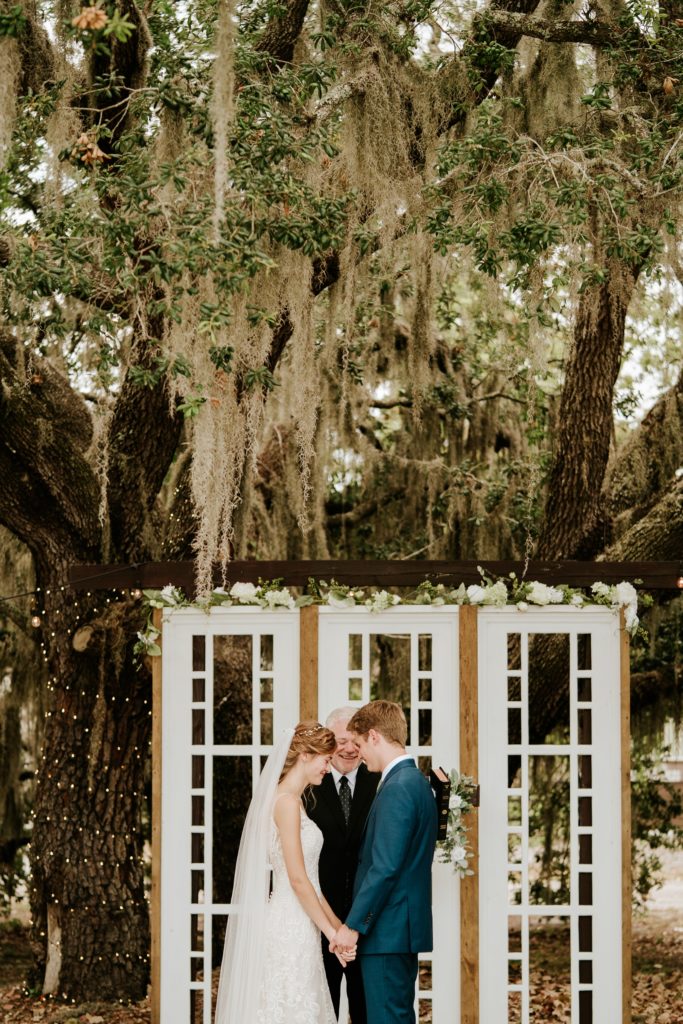 Wedding ceremony prayer under spanish moss tree at Ever After Farms Ranch