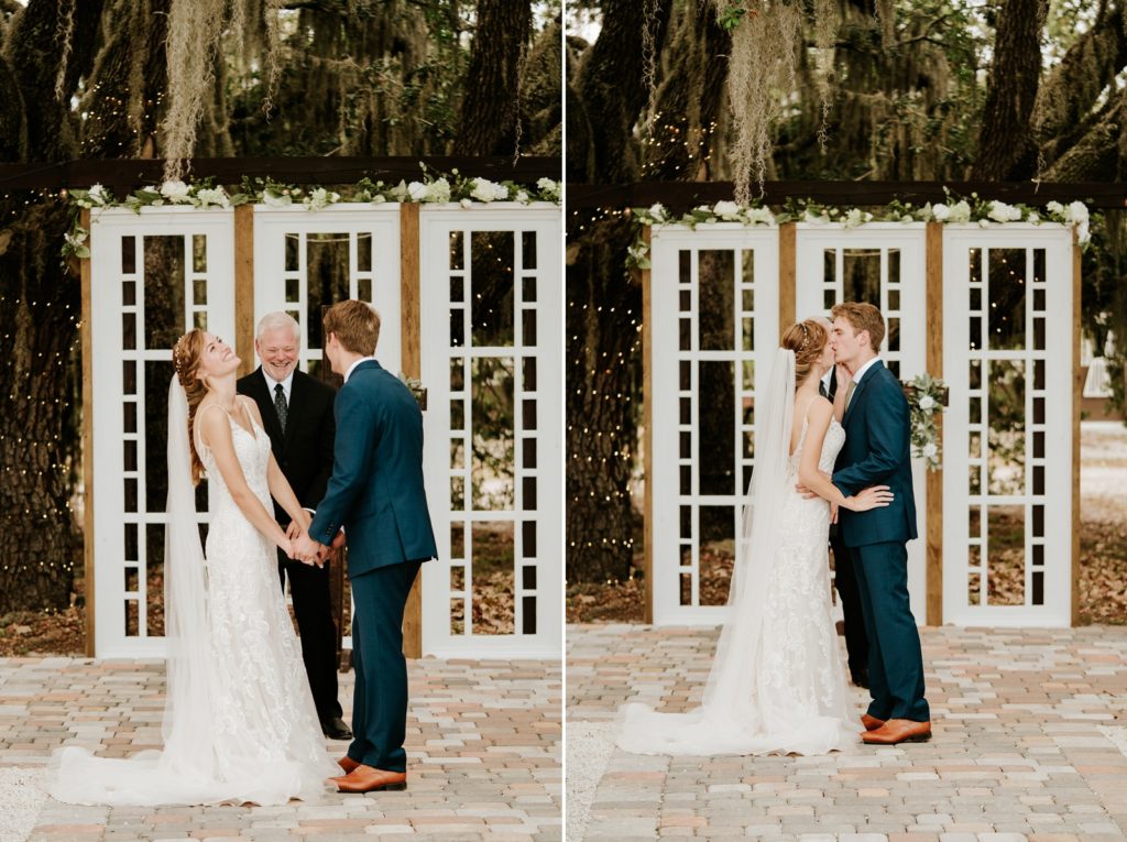 Bride and groom hold hands and laugh and share first kiss at wedding ceremony