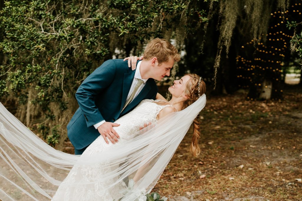 Groom dips bride with veil flowing in the wind at Ever After Farms Ranch wedding