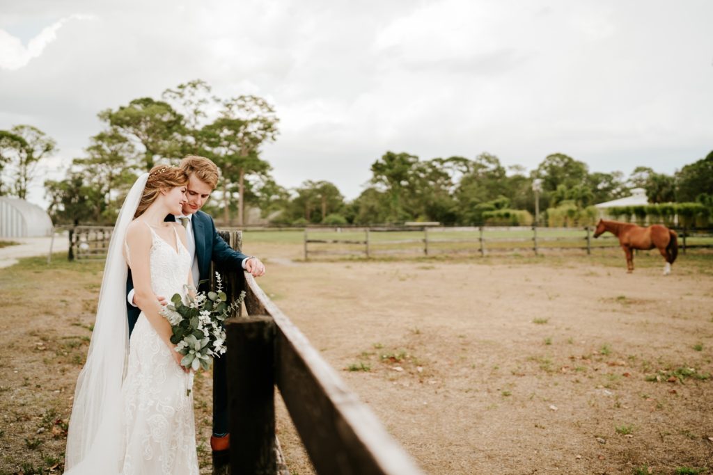 Bride and groom snuggle by fence at Ever After Farms Ranch