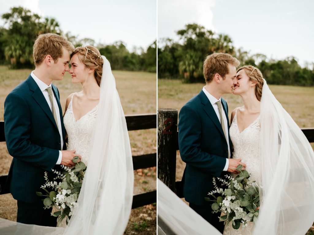 Bride and groom touch foreheads and kiss by wood fence at Ever After Farms Ranch wedding