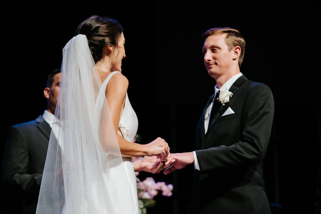 Bride and groom exchange rings indoor wedding ceremony