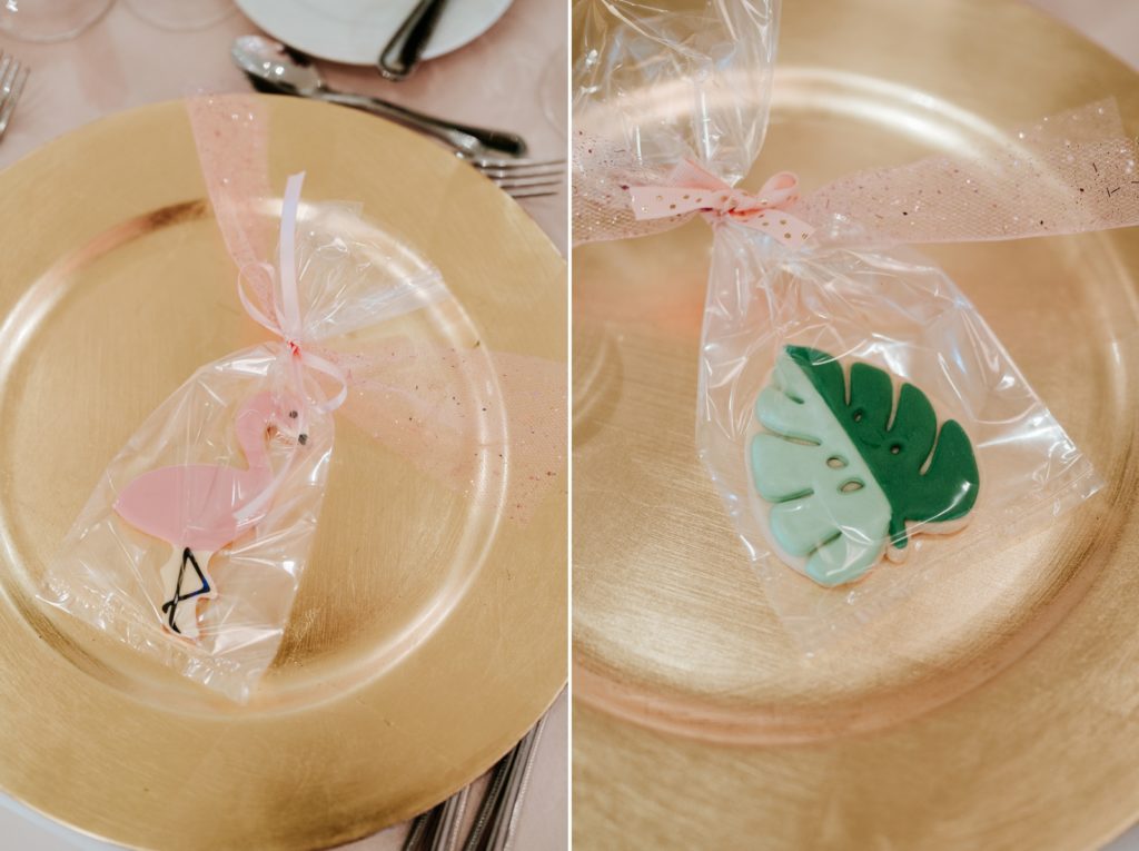 Pink flamingo and green palm cookie wedding favors on gold chargers