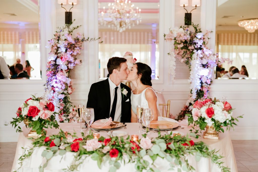 Bride and groom kiss at sweetheart table in Breakers West wedding reception Palm Beach FL