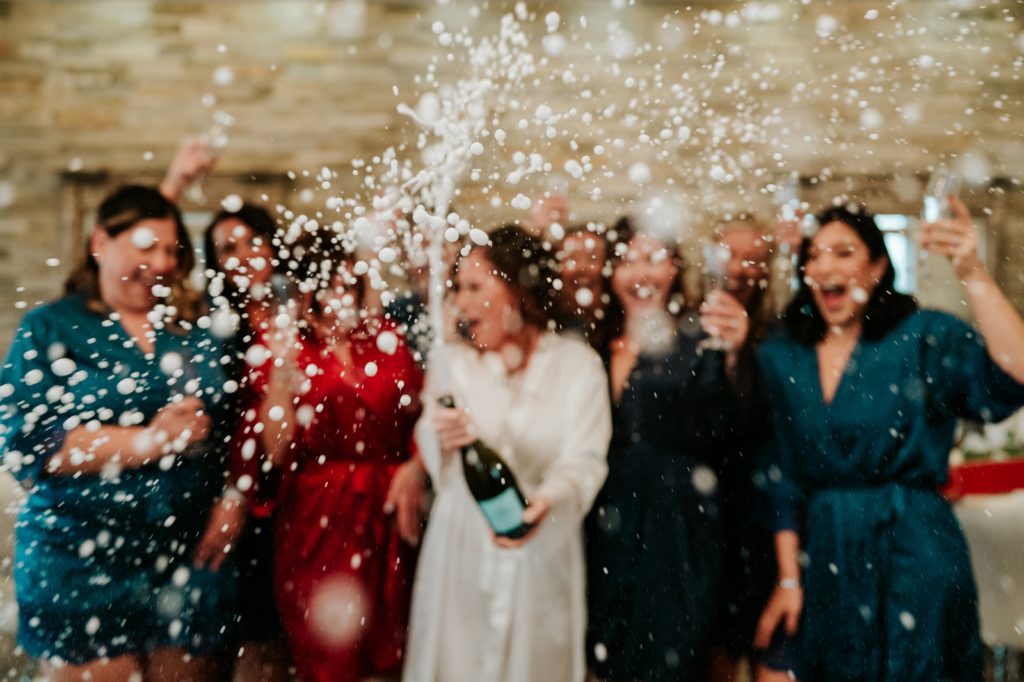 Bride sprays bottle of champagne all over bridal party