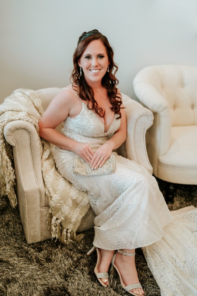 Bridal portrait in lace wedding dress with rhinestone and pearl clutch at Pellegrino's Salon & Spa