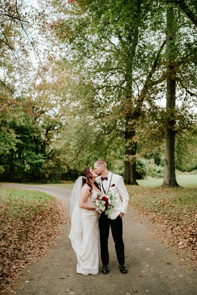 Couple kissing on road in fall leaves at Bensalen Township Country Club wedding