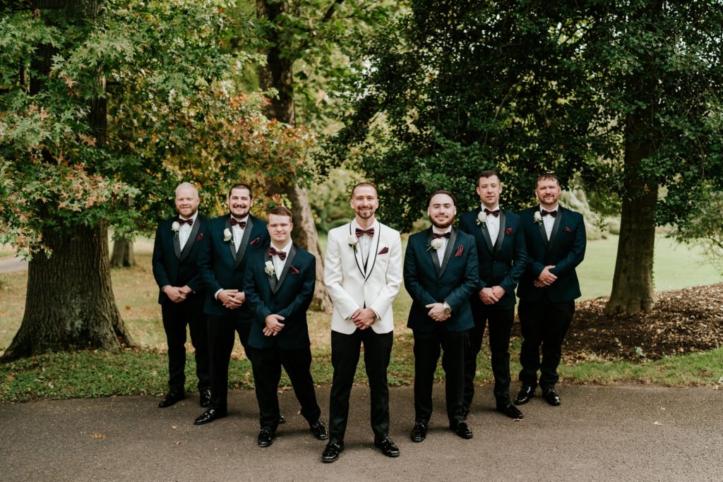 Groom in white suit poses with groomsmen in blue suits at Bensalem Township Country Club fall wedding