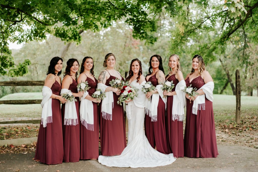 Bride poses with bridesmaids in Morilee dresses and white shawls at Bensalen Township Country Club fall wedding