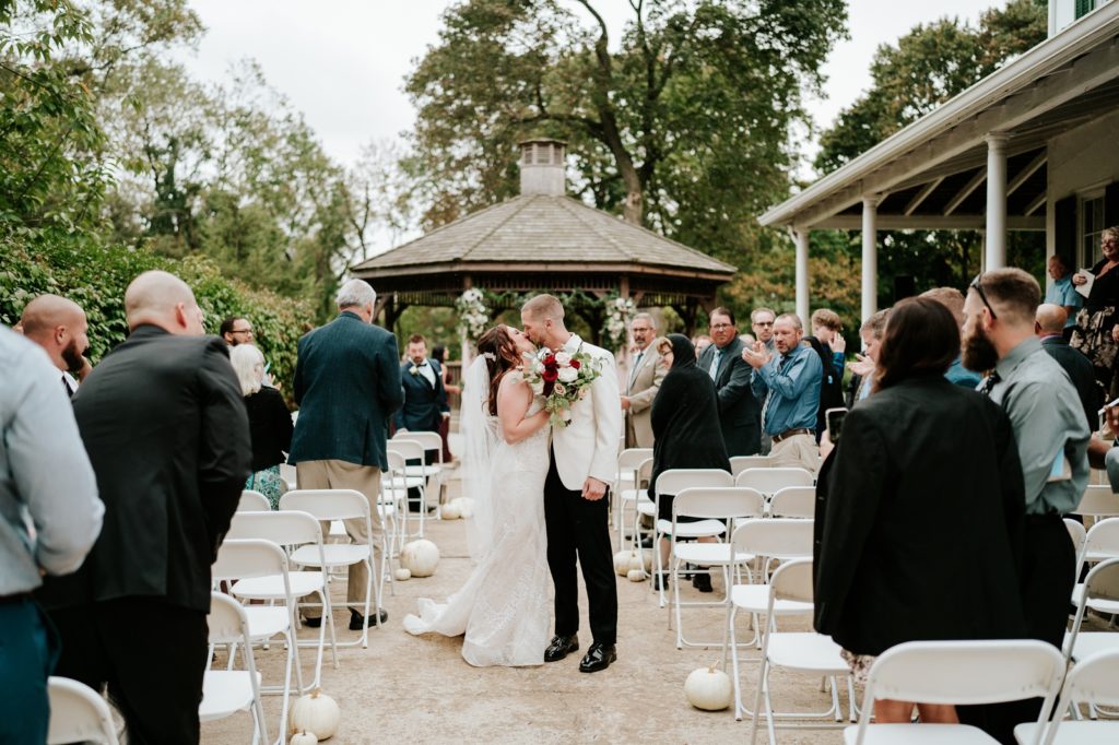 Newlyweds kiss in front of gazebo after ceremony at Bensalen Township Country Club wedding
