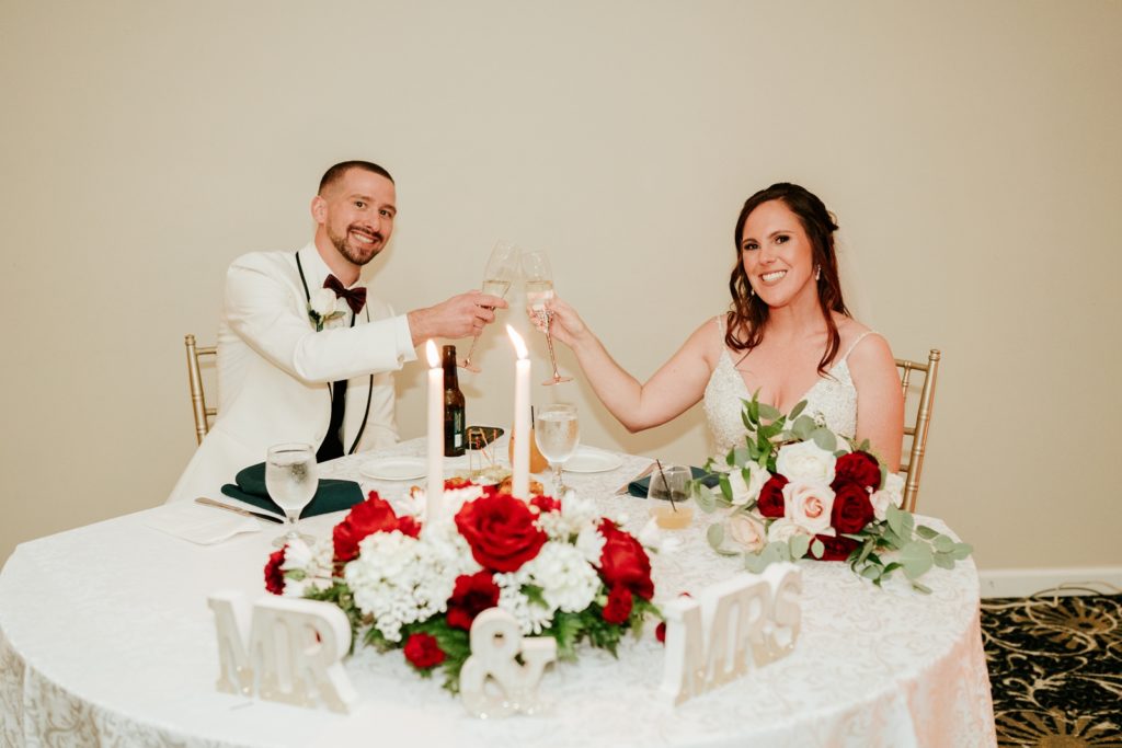 Newlywed couple clink glasses at sweetheart table
