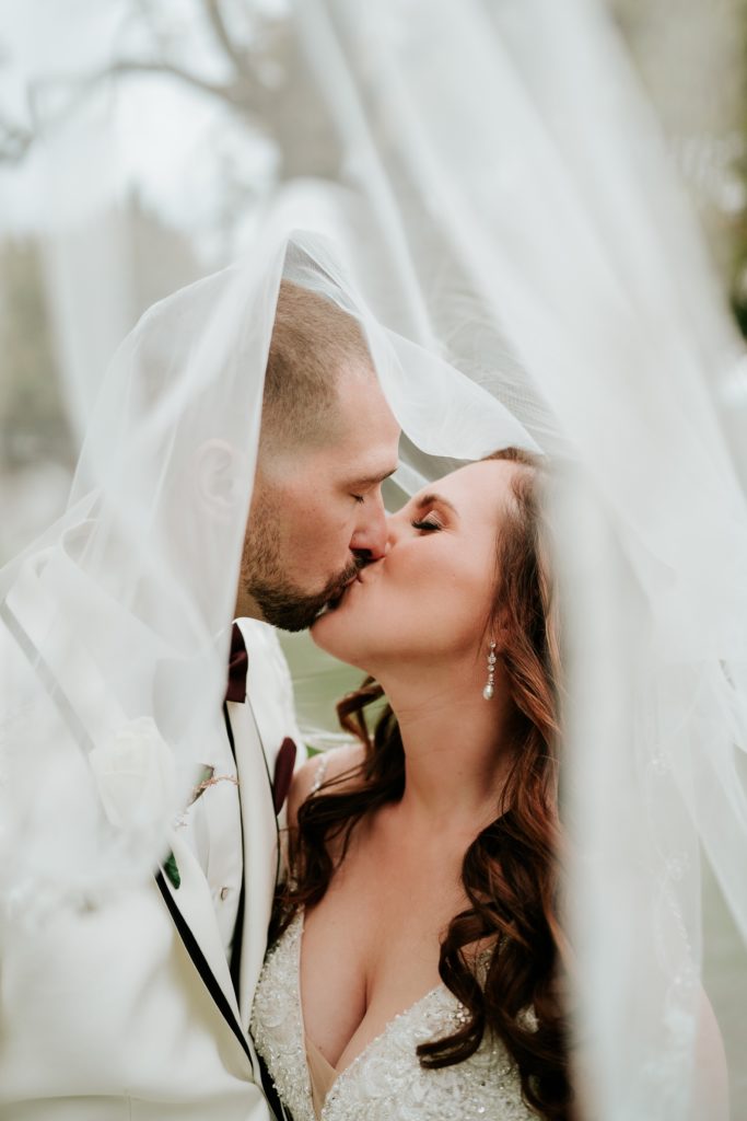 Bride and groom kiss under veil Bensalem Township Country Club