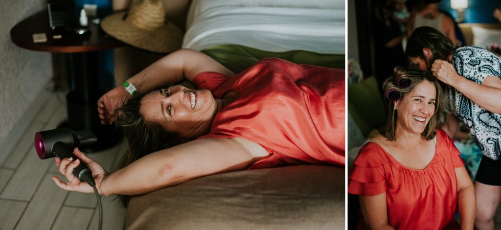Mother of the bride in pajamas blow drying her hair while laying on a bed