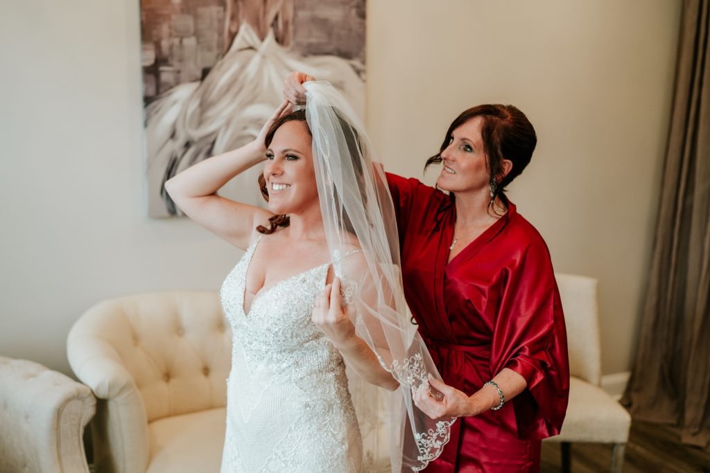 Bride smiles as mom puts on wedding veil at Pellegrino's Salon & Suite