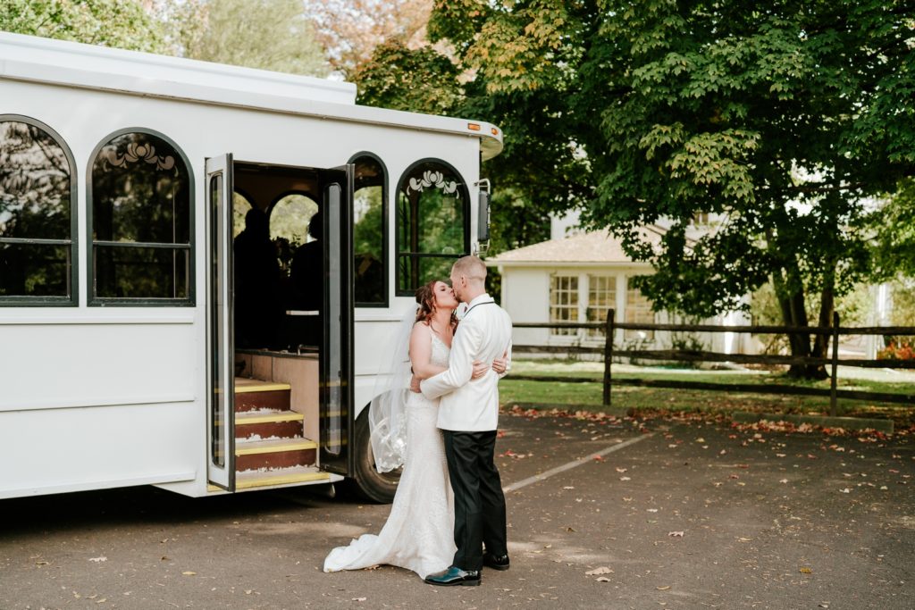 Bride and groom kiss after first look in front of wedding trolley at Bensalem Township Country Club