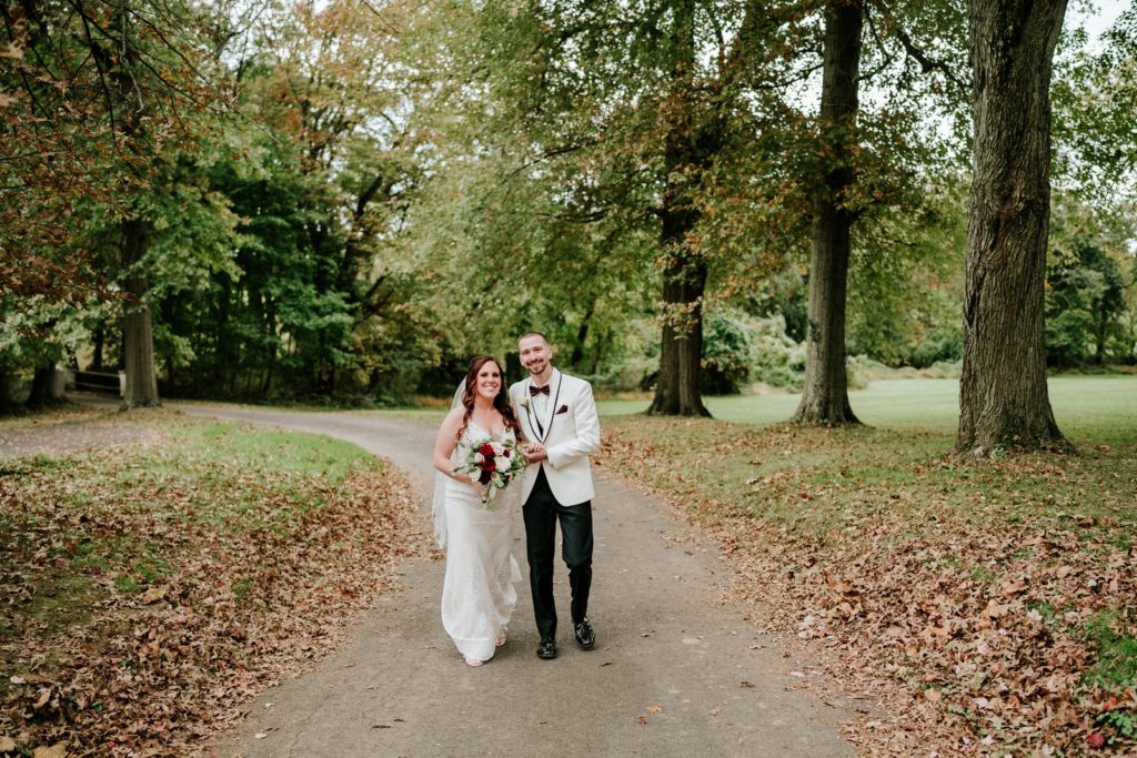 Couple walk on road in fall leaves at Bensalen Township Country Club wedding