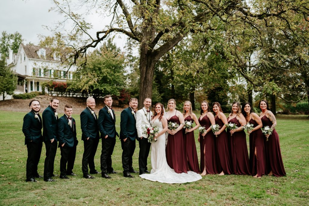 Wedding party stand together under tree at Bensalen Township Country Club fall wedding
