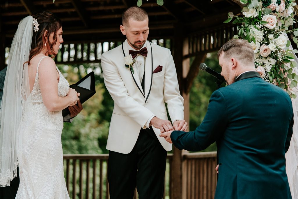 Groom takes wedding rings from best man during ceremony