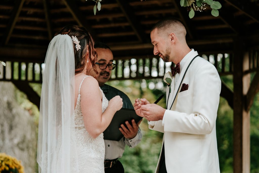 Groom holds wedding ring during wedding ceremony