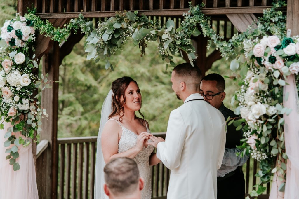 Bride says vows while placing ring on groom's finger during wedding ceremony