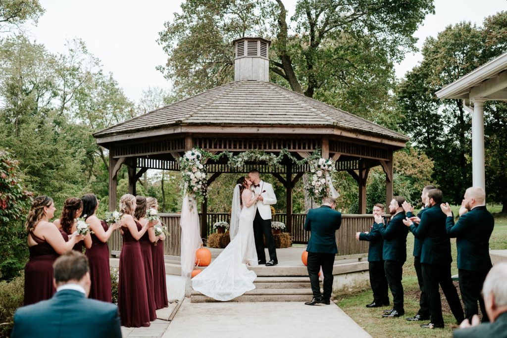 First kiss under gazebo at Bensalen Township Country Club fall wedding ceremony