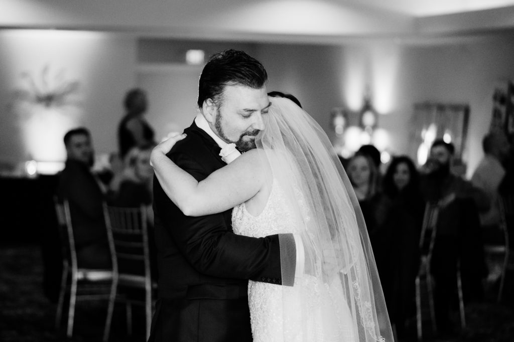 Dad hugs bride during father daughter dance at wedding reception