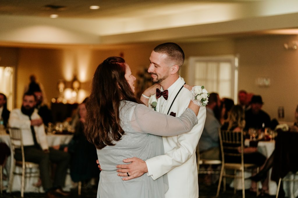 Groom smiles at mom for mother son dance at wedding reception