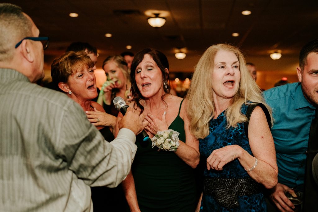 Mother of the bride sings with guests at wedding reception