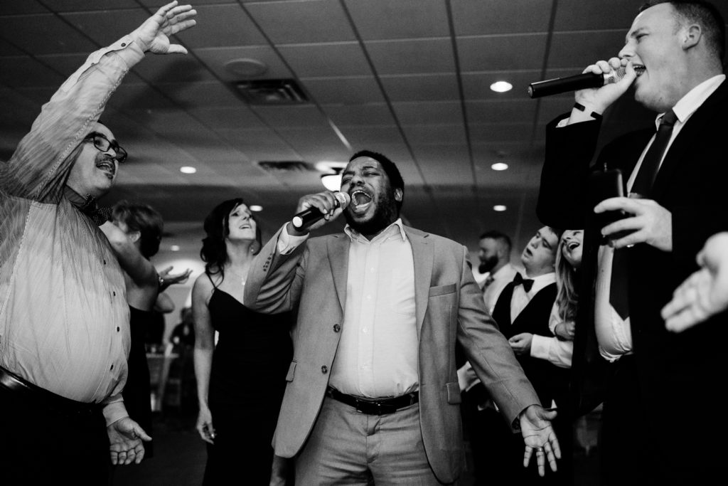 Man sings with hand outstretched into microphone at wedding reception